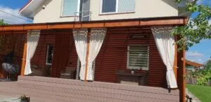 Baltos plačios užuolaidos terasoje, vandens nepraleidžiančios užuolaidos atviroje terasoje, jauki terasa.
