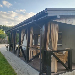 Terasos užuolaidos pakabintos medinėje terasoje, kakavinės terasos užuolaidos apsaugo nuo saulės spindulių ir pašalinių žvilgsnių.