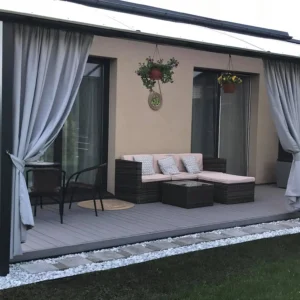 Terasa, kurią puošia pilkos spalvos lauko užuolaidos