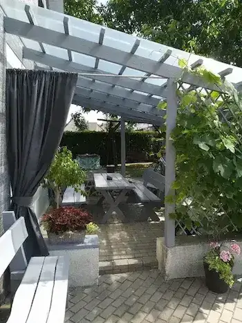 Pilkos užuolaidos terasai tarp gėlių ir augalų